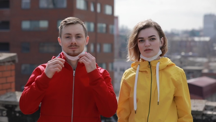 Virus epidemic, man and woman wearing face medical mask on the roof under city