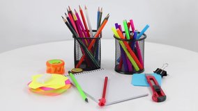 Colored office supplies on white wooden spinning table background. FHD.