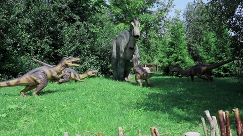 Minsk, Belarus, 08.2019 Group of Velociraptors attacks and bites Corythosaurus. Dinosaur pangolin in helmet has a large bone crest at the crown. Cretaceous period of existence.