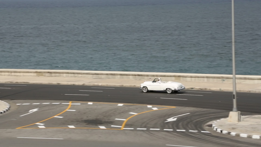 Vintage Car Driving Down Main Havana Highway Passing Cuban Flag