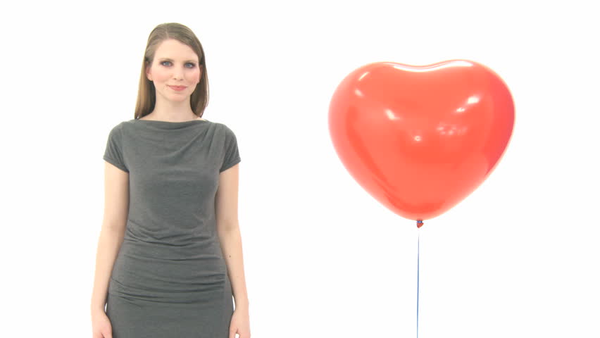 Woman standing next to heart balloon as it floats away 