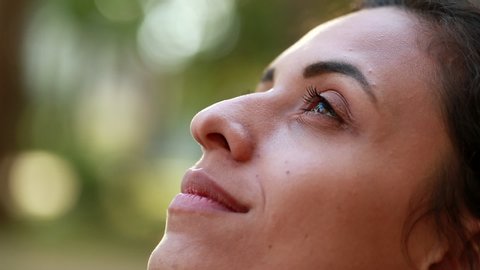 Woman looking up to the sky with hope and faith, contemplative close-up girl face