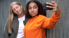 Video clip of pretty blonde girl and mixed race teenager young women taking selfies on their smart phones for social media