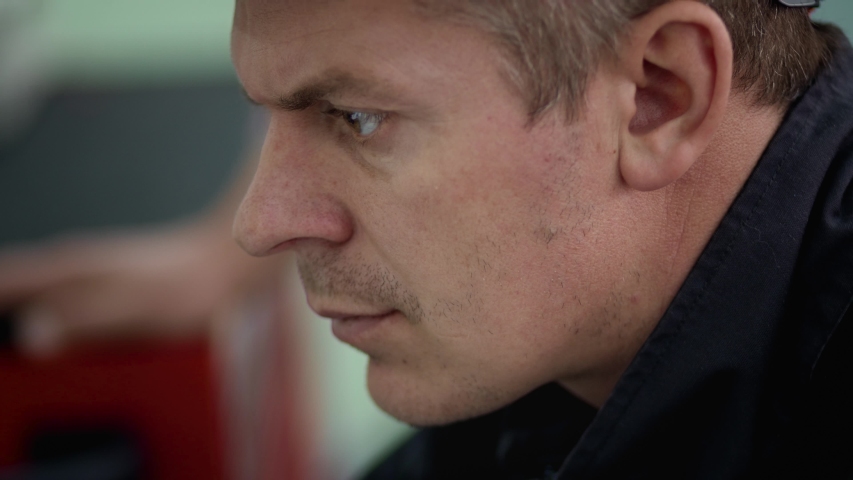 The helmeted worker looks closely at the laptop. He is preparing to start the engine. Close-up to Face.