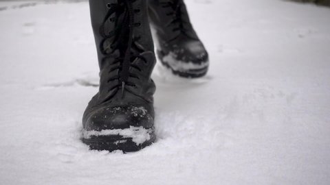 Front view of a man wearing combat boots steps on snow powerfully in slow motion - soldier, army, war, violence
