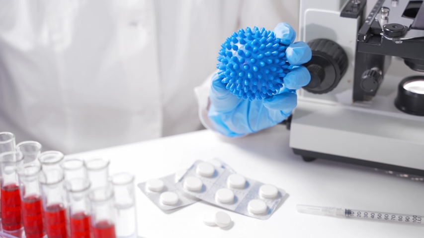 A scientist in the laboratory holds a 2019-nCoV coronavirus model. Concept - development of a vaccine or medicine against coronavirus, pneumonia epidemic in China Royalty-Free Stock Footage #1048358155