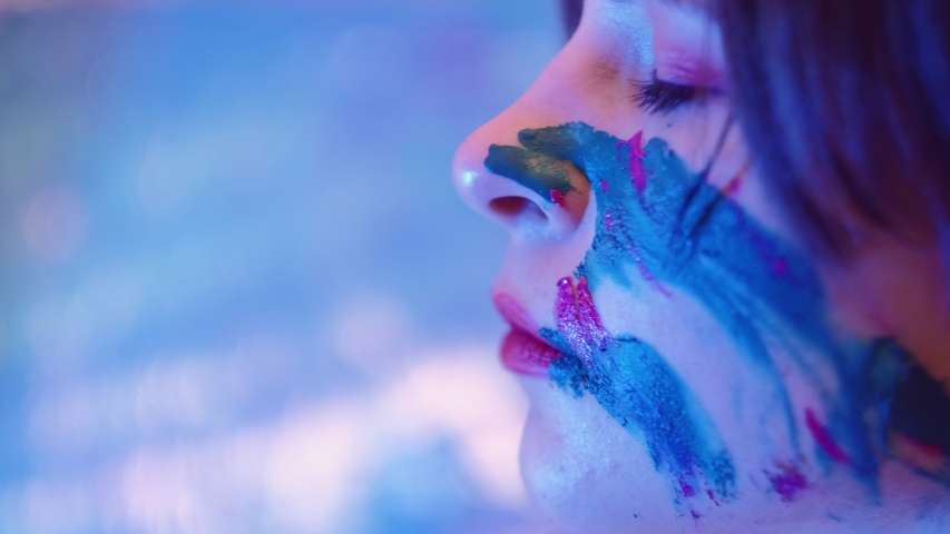 Art therapy. Soul healing. Peaceful woman with paint on face skin daydreaming with eyes closed.