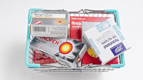 London / UK - March 15th 2020 - Packs of pain relief medication are dropped into a small shopping basket. Stockpiling medicine concept