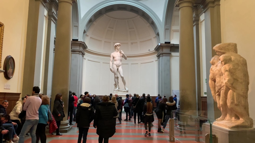 Florence, Italy -  January 25, 2020: People inside of famous Florence Accademia art museum gallery looking at view of David statue of Michelangelo
