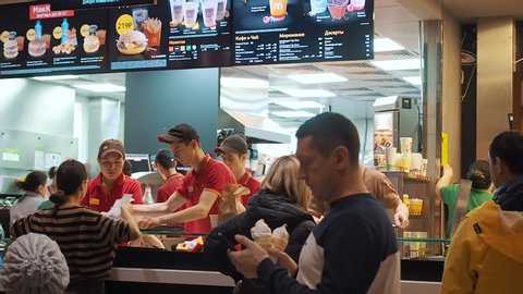 Moscow, Russia - December 15, 2019: Customers waiting for their takeaway food in the area of issuing orders in the McDonald's restaurant. Counter service in a McDonald's. A friendly managers of