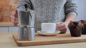 Woman preparing coffee for breakfast and pouring it in cup, slow motion video