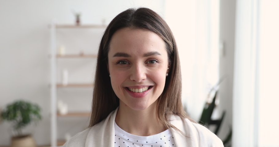 Beautiful healthy millennial single woman looking at camera at home. Happy young adult girl with attractive face standing in apartment. Smiling confident casual model posing indoors, close up portrait | Shutterstock HD Video #1048391236