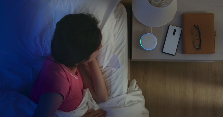 IOT AI smart home concept - Asian woman talk with voice assistant to turn on the lights of house at home while sleeping | Shutterstock HD Video #1048393237