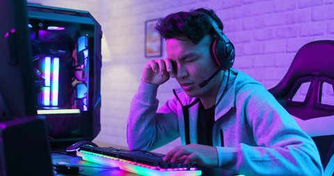 Young asian esport gamer feel painful while playing in Online Video Game because his eye is tired