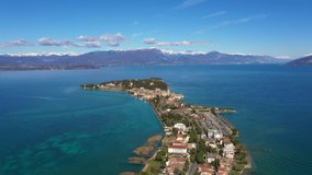 Aerial view of Sirmione Lake Garda Italy. Drone video recording 4k. In the background mountains in the snow and blue sky.