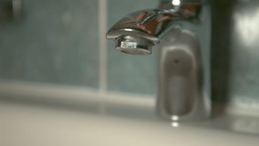 SLOW MOTION, CLOSE UP, DOF: Unrecognizable person opens the faucet to wash their hands. Glassy water starts flowing from the shiny metal bathroom tap. Crystal clear tap water streaming into the sink. - Powered by Shutterstock - Get 15% off with code: PIKWIZARD15