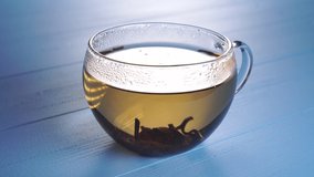 Dessert spoon stirs the petals of herbal tea in a glass cup on a blue wooden background - Powered by Shutterstock - Get 15% off with code: PIKWIZARD15