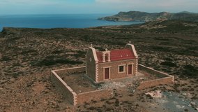 Flies around a lonely Orthodox church on the Mediterranean coast and the island of Crete, near the church a fence is destroyed, around no one, aerial video