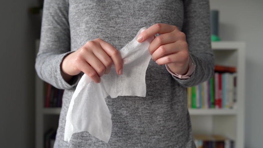 Close up on midsection of young caucasian woman hands wiping using white alcohol tissue cleaning disinfection from virus and bacteria in day at home or office front view  | Shutterstock HD Video #1048416481