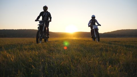 Motorcyclists riding from sunset on their motorbikes. Friends having active rest driving powerful motorcycles at sundown. Bikers enjoying ride. Extreme sport concept. Scenic landscape. Low view