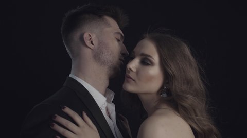 Man and woman in stylish clothes kiss. Couple man and woman on dark background. Perfume advertising.  Love and kisses.