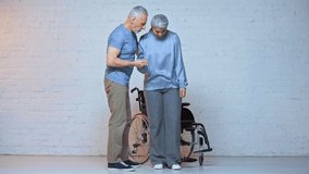 caring senior man helping asian wife near wheelchair