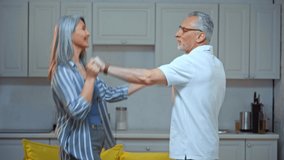 happy senior and interracial couple dancing at home