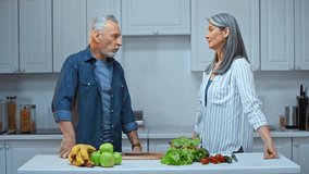 senior and interracial couple talking in kitchen