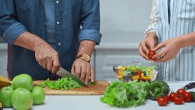 cropped view of senior couple preparing salad in kitchen