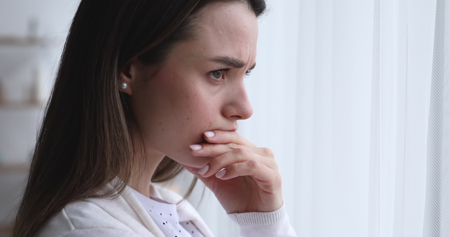 Depressed worried beautiful young woman feeling nervous, upset about problem. Anxious sad doubtful girl reflecting, looking through window and thinking of mental stress concept. Close up side face Royalty-Free Stock Footage #1048429240