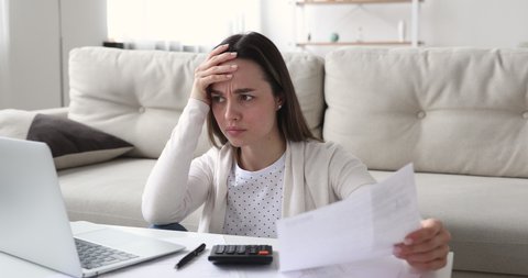 Angry young woman feeling stressed by high taxes, bills or mortgage rate. Annoyed female renter calculating household payments. Frustrated customer counting bank debt invoice worried about mistake.