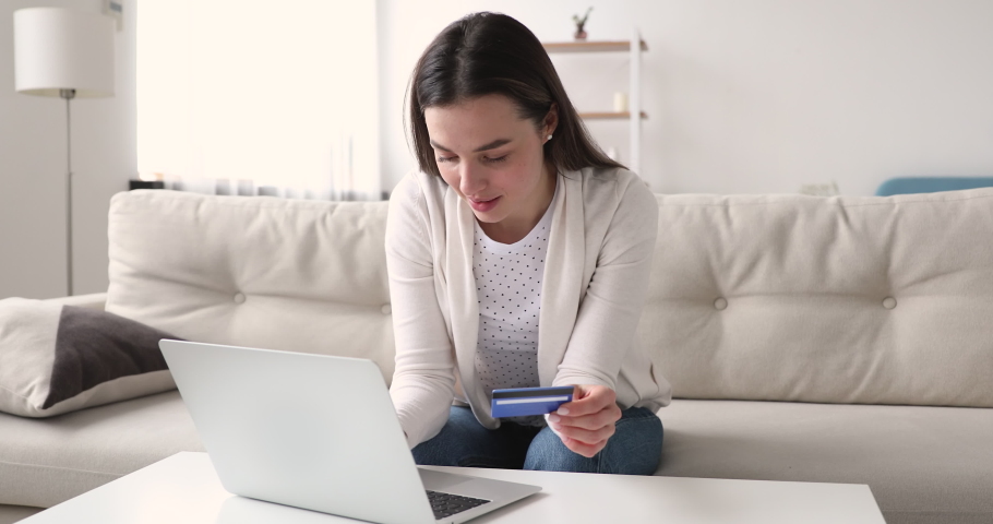 Millennial woman shopper holding credit debit card making order at home. Young female customer using laptop doing internet shopping paying for purchase on website. Secure online payment concept Royalty-Free Stock Footage #1048429327