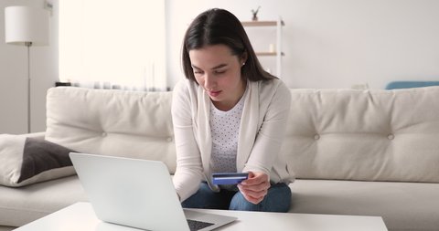 Millennial woman shopper holding credit debit card making order at home. Young female customer using laptop doing internet shopping paying for purchase on website. Secure online payment concept