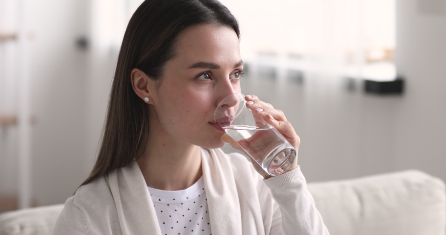 Attractive healthy millennial woman holding glass drinking fresh mineral water at home. Thirsty young lady hydrating thirst tasting pure water in the morning for diet and weight loss balance concept. Royalty-Free Stock Footage #1048429348