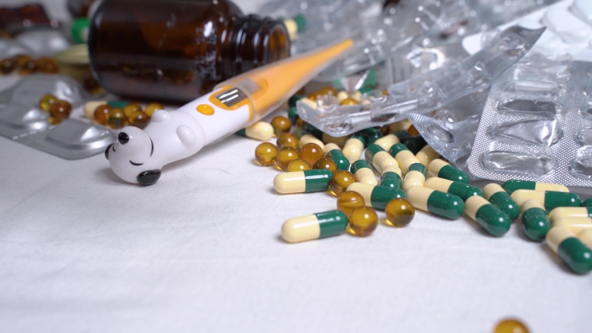 Close up of a dog paw sorting out various pills on a white table. The concept of pharmacy, medecine and treatment.