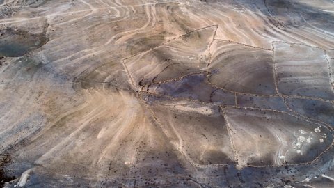 Amazing drone view of rough rocky terrain with trails on sunny day in countryside