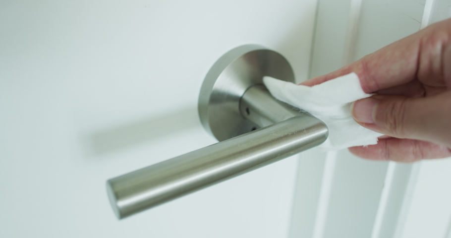 Coronavirus COVID-19 Prevention cleaning woman wiping doorknob with antibacterial disinfecting wipe for killing corona virus on surfaces or touching public bathroom handle with tissue. | Shutterstock HD Video #1048474729