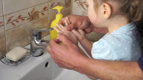 Protection and disinfection against coronavirus (COVID-19). Dad washes a small child's hands with soap over the sink with running water. Personal hygiene