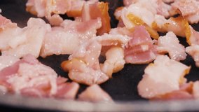 Finely chopped bacon is fried in hot oil in a pan.