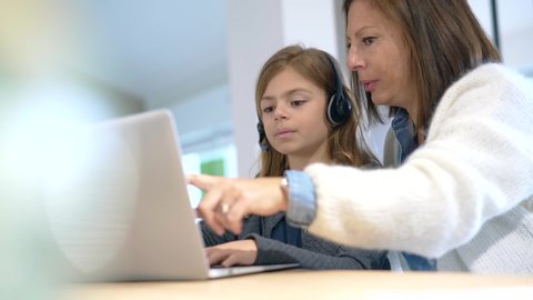 Mother and kid at home doing school teaching online