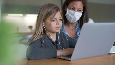 Woman at home with kid helping with online teaching - coronavirus