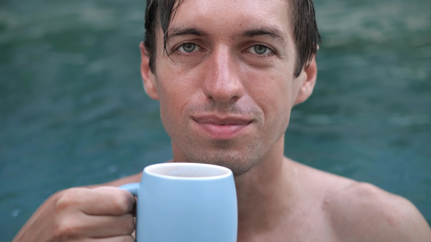 Young man on vacation drinking coffee in a swimming pool
