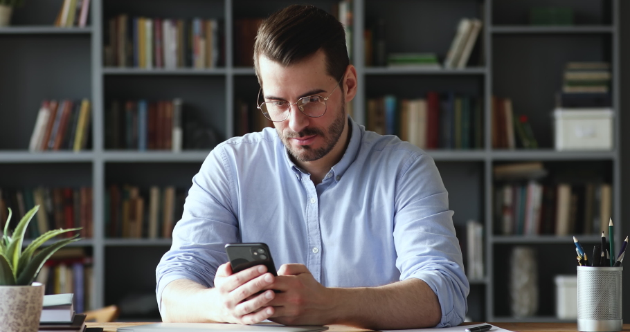 Amazed happy businessman receiving sms message reading good news. Excited overjoyed male winner celebrating success looking at smart phone sitting at home office desk. Mobile victory concept Royalty-Free Stock Footage #1048491169