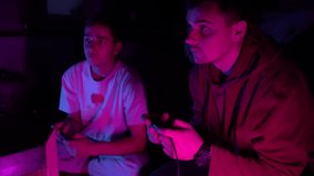 Guys playing video games in dark room by light of television