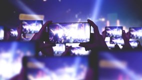 The crowd watches a concert, sings, jumps. Gold confetti floating in the air during a concert. Fans are recording videos on smartphones. A lot of smartphones. Live Stream. Stories.Strobing stage light