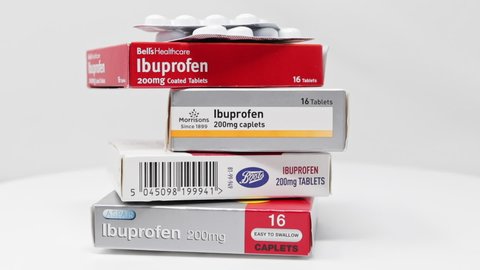 London / UK - March 17th 2020 - Stack of Ibuprofen anti-inflammatory medication boxes and packet of tablet blister packs slowly rotating on a white background. 
