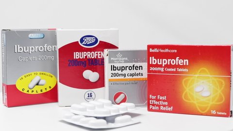 London / UK - March 17th 2020 - Supermarket brands of Ibuprofen anti-inflammatory medication boxes and packs of tablets slowly rotating on a white background. 