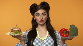 Unsure pin up woman holding burger and fresh vegetables