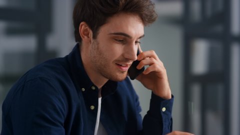 Closeup smiling man talking mobile phone in office. Close up of cheerful businessman having phone call at workplace in slow motion. Portrait of happy business man calling phone indoor.