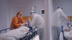 Doctor in Protective Suit Putting on Oxygen Mask on Patient Suffering from Coronavirus - Wide Dolly Shot in Slow Motion - Powered by Shutterstock - Get 15% off with code: PIKWIZARD15